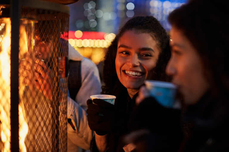 Friends having a conversation with hot drinks in a festive environment.