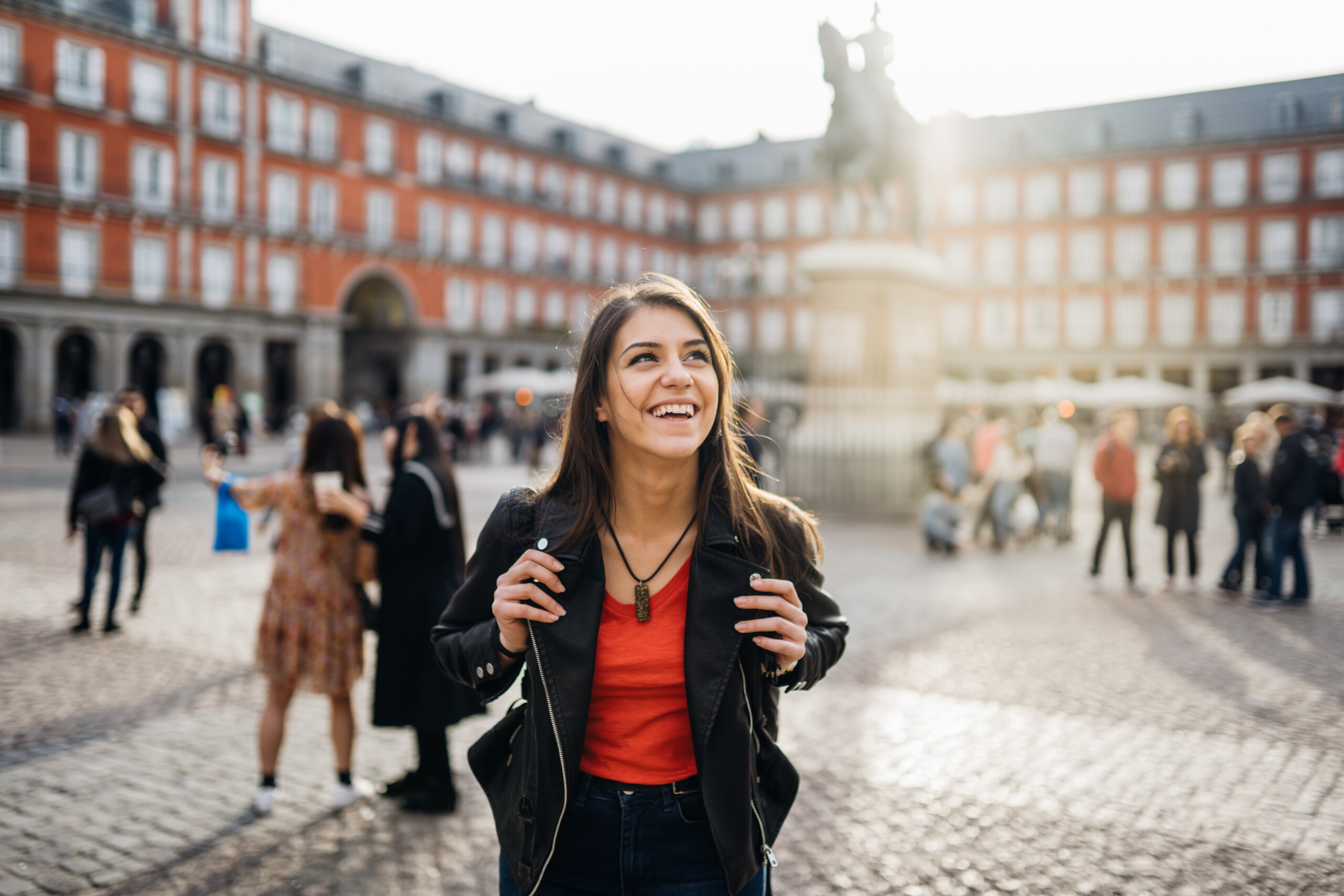 Young woman exploring the city centre. She is happy and looking up past the camera to a landmark